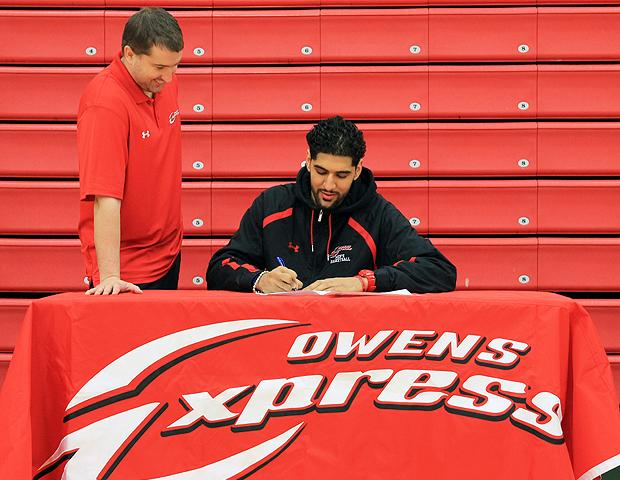 Bikramjit Gill signs his letter of intent with Ball State as Owens men's basketball head coach Dave Clarke looks on. Photo by Geoff Roberts/Owens Sports Information