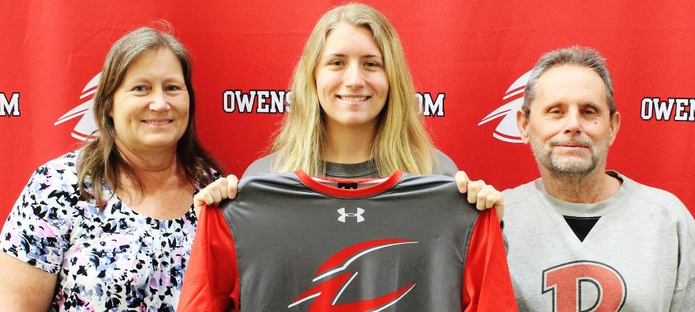 Kerri Clark, pictured with her parents, holds up a jersey after signing her letter of intent. Photo by Nicholas Huenefeld/Owens Sports Information